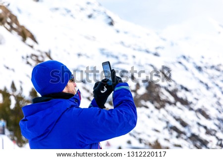 Man making photos with his phone in the snow