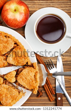 Closeup homemade apple pie with cinnamon and cup of tea on wooden table. Top view.