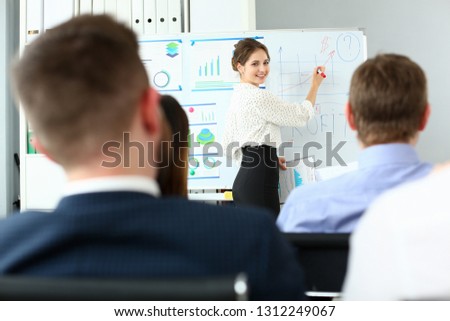 Young beauty teacher woman in class room workgroup seminar board with chart coaching background. Lecturer applicants retraining financial statistics management enterprise etiquette corporate spirit Royalty-Free Stock Photo #1312249067