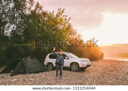 woman taking picture of sunrise on her phone. car camping. lifestyle concept