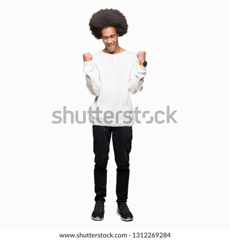 Young african american man with afro hair wearing glasses very happy and excited doing winner gesture with arms raised, smiling and screaming for success. Celebration concept.