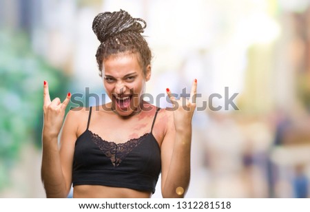 Young braided hair african american with pigmentation blemish birth mark over isolated background shouting with crazy expression doing rock symbol with hands up. Music star. Heavy concept.