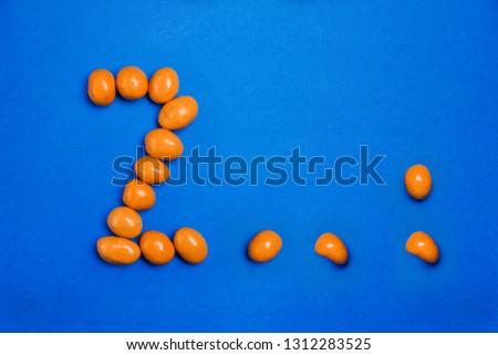Alphabet letter Z . , ; of yellow candy on blue background.