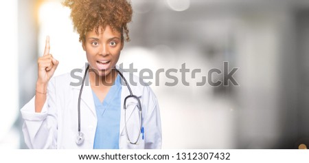 Young african american doctor woman over isolated background pointing finger up with successful idea. Exited and happy. Number one.