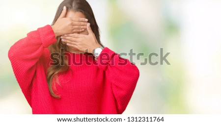 Young beautiful brunette woman wearing red winter sweater over isolated background Covering eyes and mouth with hands, surprised and shocked. Hiding emotion