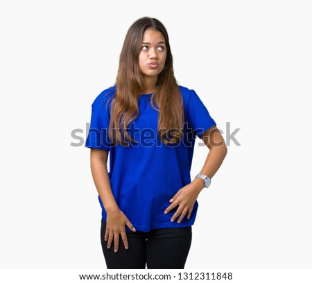 Young beautiful brunette woman wearing blue t-shirt over isolated background making fish face with lips, crazy and comical gesture. Funny expression.