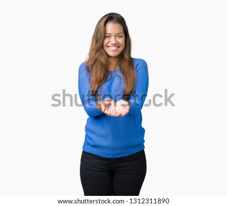 Young beautiful brunette woman wearing blue sweater over isolated background Smiling with hands palms together receiving or giving gesture. Hold and protection