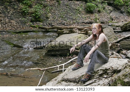 a beautiful caucasian woman sitting on a large rock