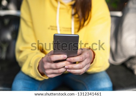 Close up cropped photo of unrecognizable person sitting inside loft interior space in coffee shop. She holding her portable telephone equipment in hands