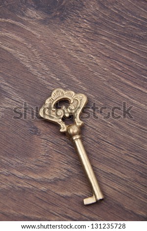 Old beautiful key with ornament on wooden background/Big key