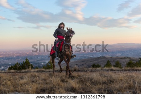 young man is riding a horse at sunset, Seljuk and Ottoman soldier riding horse