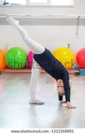 The little girl is a preschooler engaged in stretching in training. The concept of sports, education, hobbies, training and dance.