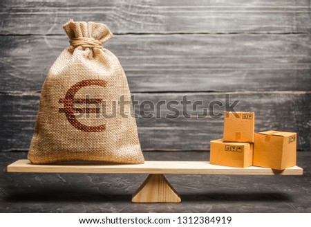 A bag of euro money and a bunch of boxes on the scales. Economic relations between subjects, the global economic model. Conceptual trade balance between countries and unions, trade and exchange goods Royalty-Free Stock Photo #1312384919
