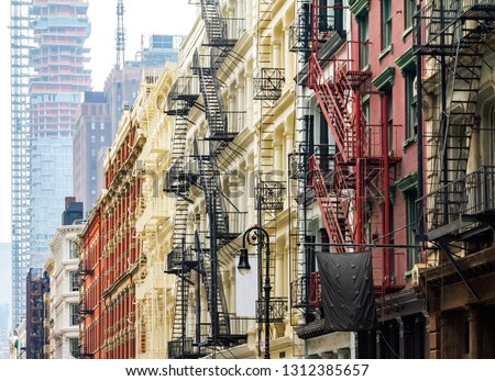 Old historic buildings along Greene Street in SoHo Manhattan contrast against the modern tower in the background Manhattan skyline in New York City