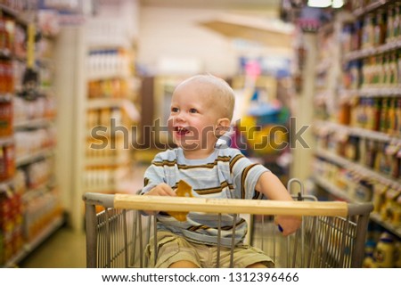 Male toddler sitting in a shopping cart looking delighted