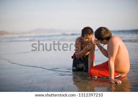 Boys looking for creatures in the sand at the beach