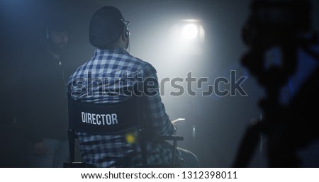 Medium shot of a director sitting in his chair on a film set Royalty-Free Stock Photo #1312398011