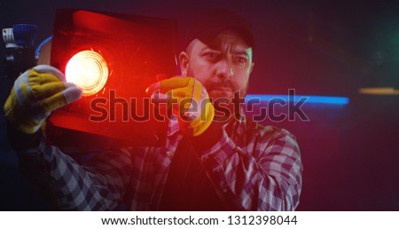 Medium shot of a cameraman testing a Fresnel lamp with red lighting gel