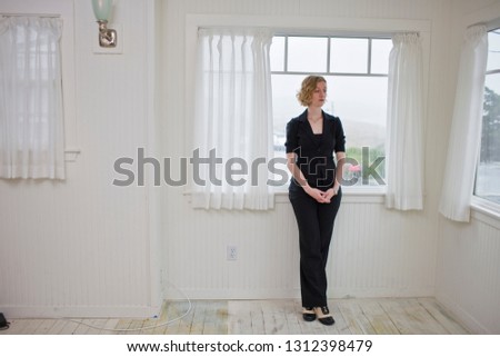 Woman standing in house next to window