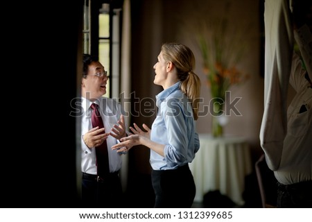 Two business colleagues having an animated conversation with each other inside a restaurant.