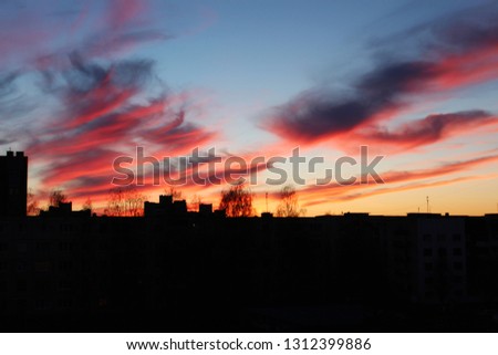 Spectacular burning sunset in the dark blue sky above city buildings in the evening of a spring day 