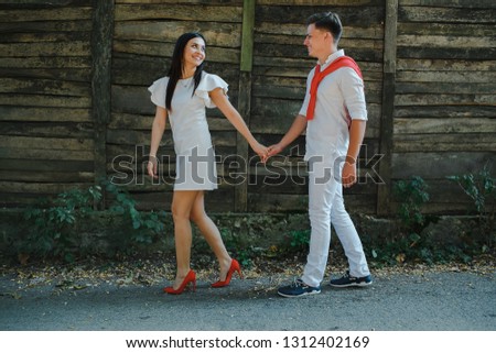 Young and happy couple standing on a wooden background.
