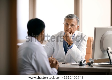 Friendly senior doctor consulting with a patient in his office.