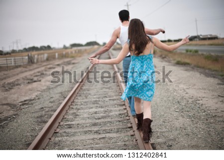 Young couple balancing on train tracks together