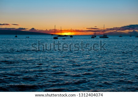 Silhouette of moored boats with sun setting in the background.