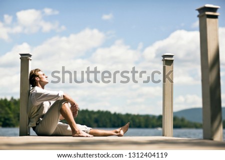 Man relaxing on a jetty by a lake.