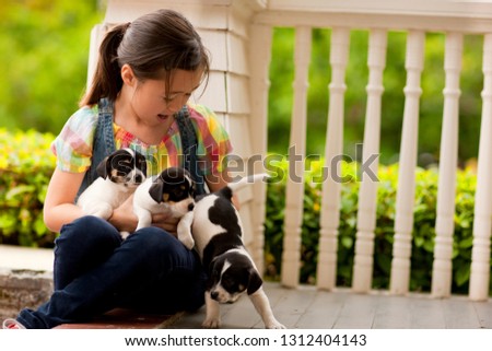 Portrait of young girl on front stoop with a litter of puppies.