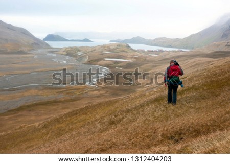 Photographer walking through countryside while carrying his equipment.