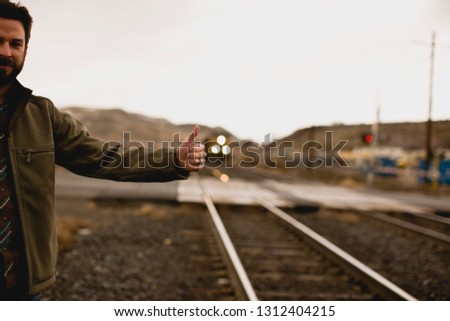 Man hitchhiking by train tracks.