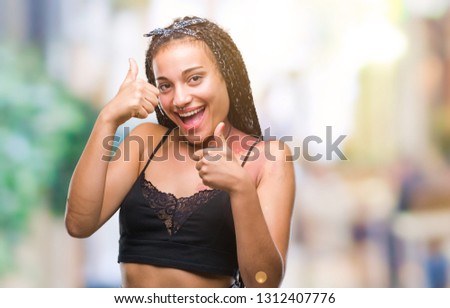 Young braided hair african american with pigmentation blemish birth mark over isolated background doing happy thumbs up gesture with hand. Approving expression looking at the camera