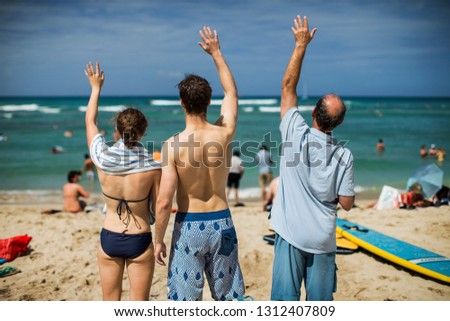 Young adults standing with their father on a beach.