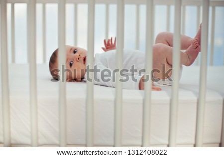 Portrait of a baby boy waving his legs in the air as he lies his crib.
