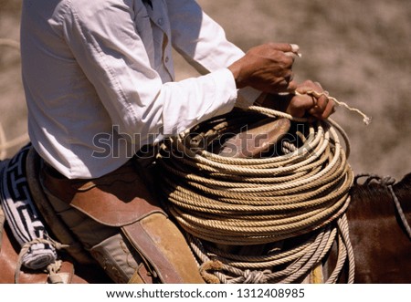Cowboy holding a coil of rope at the front of his saddle.