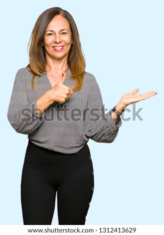 Beautiful middle age business woman Showing palm hand and doing ok gesture with thumbs up, smiling happy and cheerful