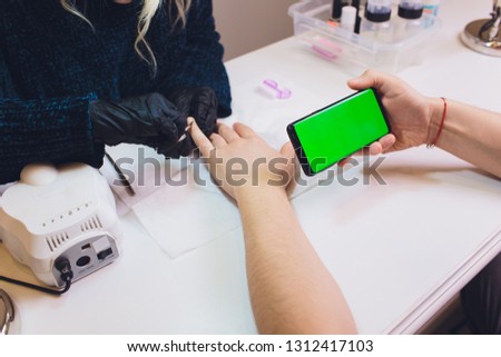 Hands in gloves cares about man's hand nails. Manicure beauty salon. smartphone, green screen, hromakey