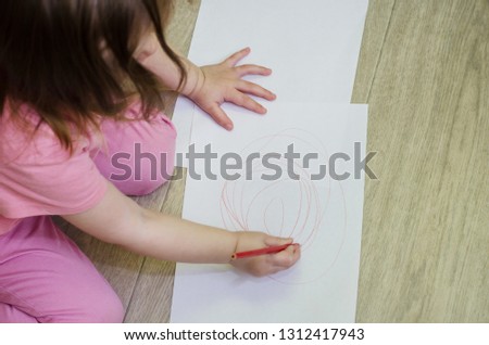 little girl draws with colored pencils on the floor