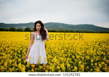 young woman surrounded by flowers in a rape field