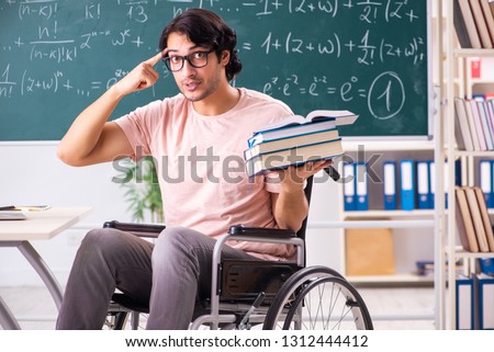 Young handsome man in wheelchair in front of chalkboard