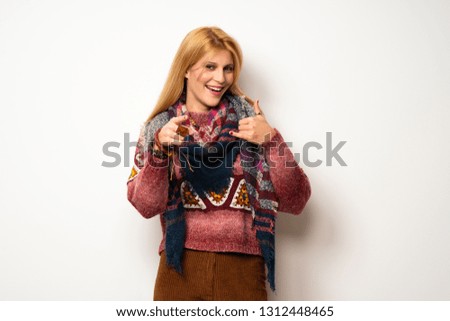 Hippie woman over white wall making phone gesture and pointing front