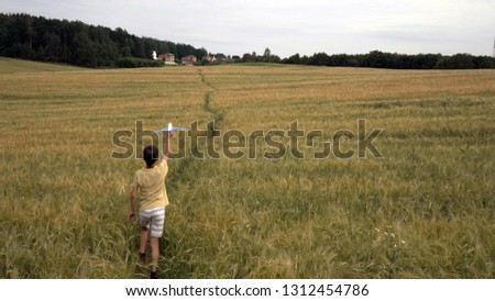 Happy teen boy playing with toy airplane against beautiful nature background
