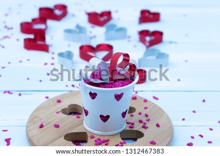 Valentines day concept or Women day concept. Red and white hearts on the pink gravel top of the bucket with sky blue wooden background.