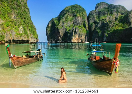 Young woman sitting on the beach at  Maya Bay on Phi Phi Leh Island, Krabi Province, Thailand. This island is part of Mu Ko Phi Phi National Park.