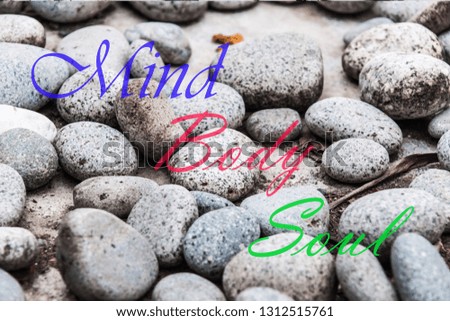Health concept of zen stones on blurred background with text of body mind soul. 