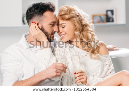 Blissful smiling couple drinking champagne at home