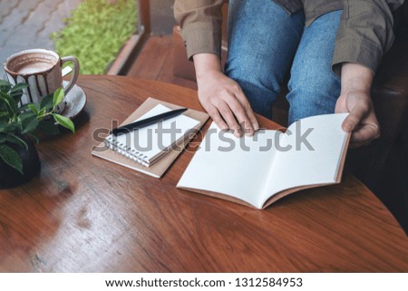 Closeup image of a woman opening a notebooks on wooden table 