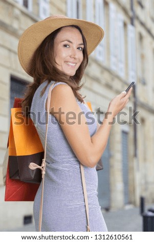 beautiful female holding paper-bags with purchases and phone